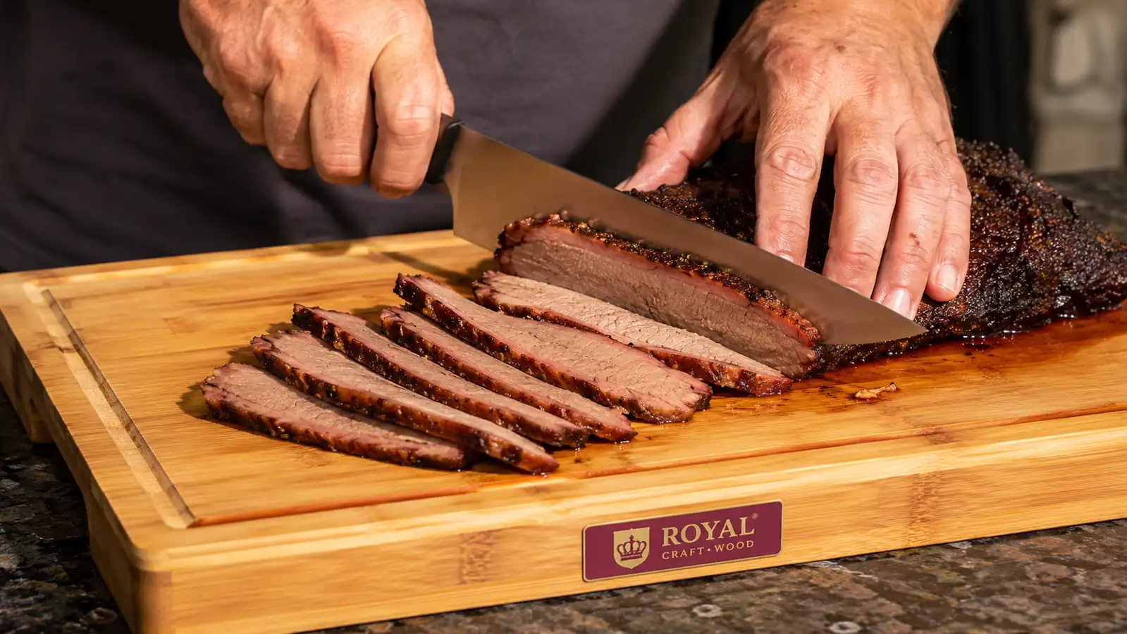 Hands using a carving knife to slice brisket on a bamboo board, juice pooling in the groove